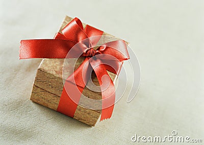 A brown gift with a red satin ribbon and a bow
