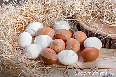 Brown and white eggs in the straw nest on wooden