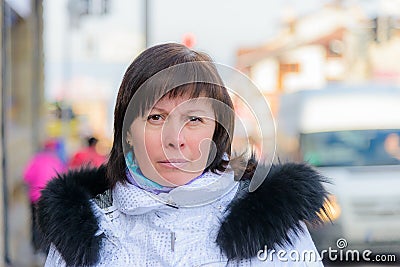Brunette middle-aged woman in a stylish white jacket with fur hood