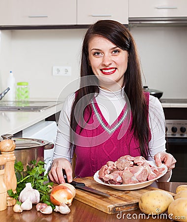 Brunette woman cooking with meat
