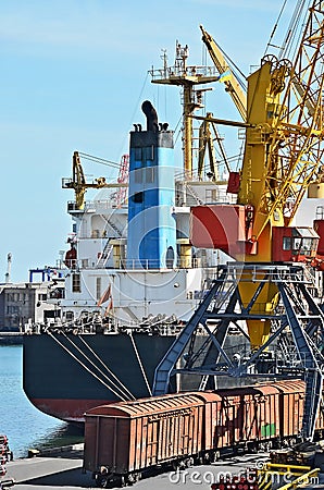 Bulk cargo ship and train under port crane
