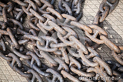 Bundle of rusty naval chains laying on pier