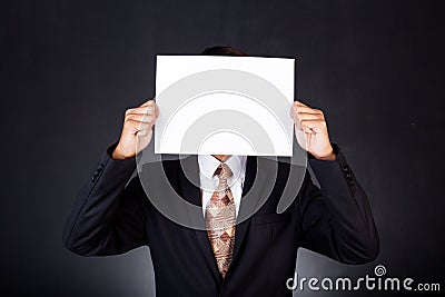 A business man holding a paper in front of his face