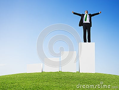 Business Man Outdoors Standing on a Bar Graph with Arms Raised