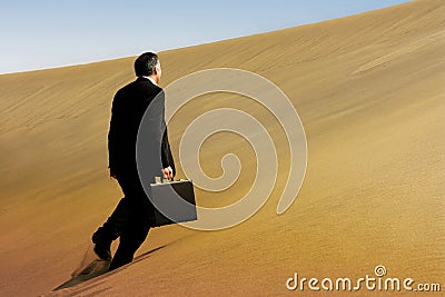 A business man running across the face of a dune