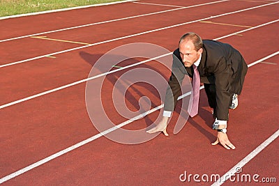 Business man on a running track ready to run