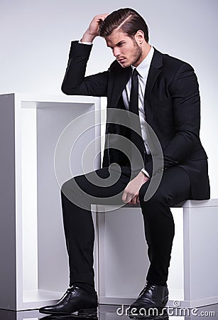 Business man sitting on a table while scratching his head