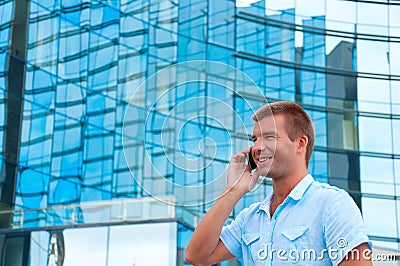 Business man speaking on phone in front of modern business building