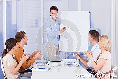 Business people clapping for colleague after presentation