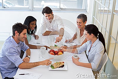 Business people eating sandwiches and fruit for lunch