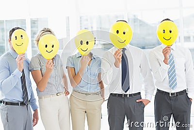 Business people holding happy smiles in front of faces