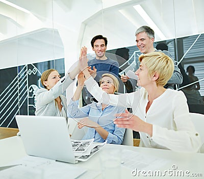 Business team with computer giving High Five