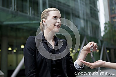 Business woman handing metal key to second person