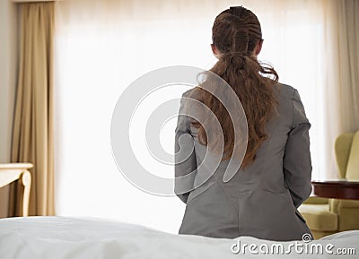 Business woman sitting on bed in hotel room