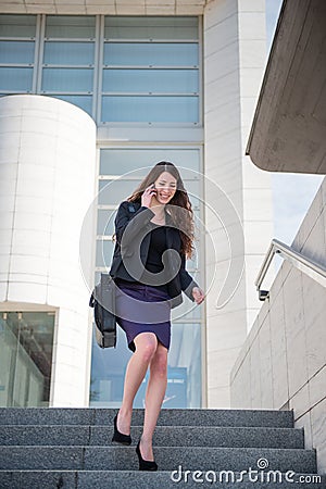 Business woman walking on stairs calling phone