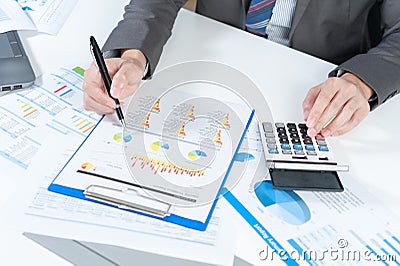 Businessman analyzing report on chart with laptop and calculator