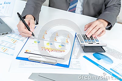 Businessman analyzing report on chart with laptop and calculator