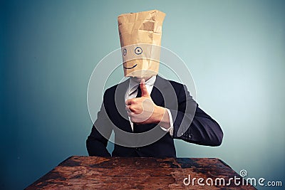 Businessman with bag over head giving thumbs up