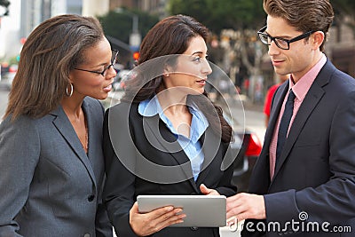 Businessman And Businesswomen Using Digital Tablet Outside