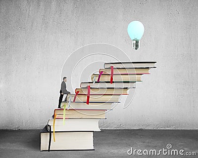 Businessman climbing on stack of books with growing bulb, buildi