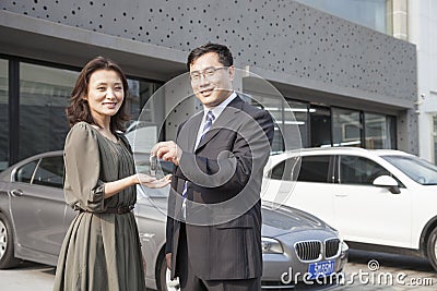 Businessman Handing Car Keys To Woman in Auto Repair Shop