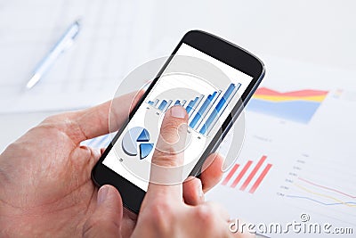 Businessman holding cell phone displaying graph