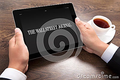 Businessman holding ipad with Wall Street Journal on the screen