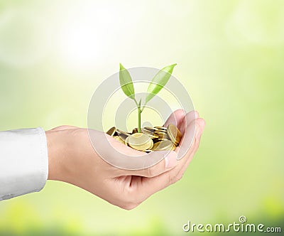 Businessman holding plant sprouting from handful of coins
