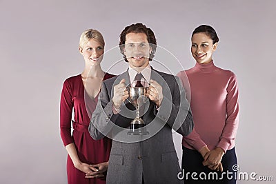 Businessman Holding Trophy With Female Colleagues