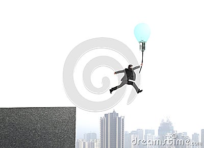 Businessman jumping from bulding top to catch glowing lamp ballo