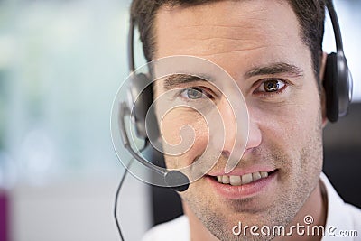 Businessman in the office on the phone with headset, looking cam
