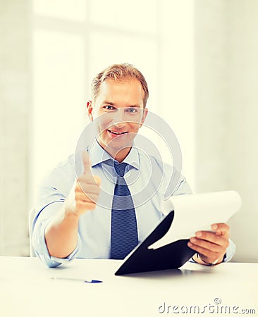 Businessman with papers showing thumbs up