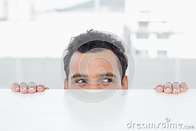 Businessman peeking behind the desk at office