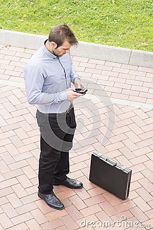 Businessman with phone and briefcase in the street.