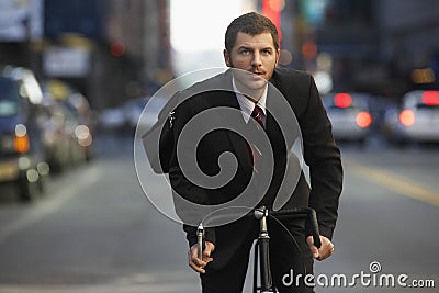 Businessman Riding Bicycle On Urban Street