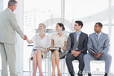 Businessman shaking hands with woman by people waiting for interview
