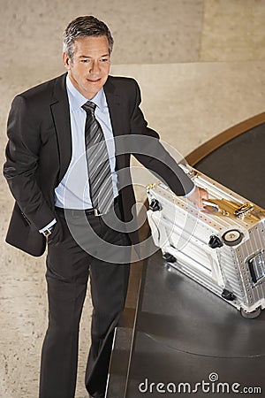Businessman With Suitcase At Luggage Carousel In Airport