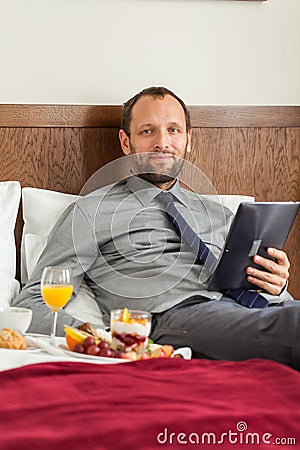 Businessman with tablet computer during breakfast. He is lying o