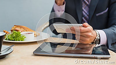 Businessman with tablet and smartphone during breakfast.