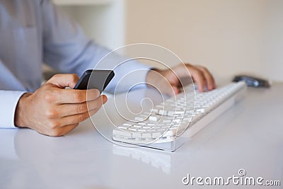 Businessman texting on phone at desk