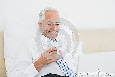 Businessman using laptop while having coffee in bed