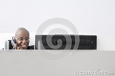 Businessman Using Telephone At Computer Desk