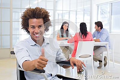 Businessman in wheelchair gives thumbs up to camera