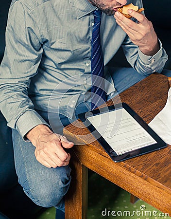 Businessman working on tablet pc during breakfast at home/hotel.