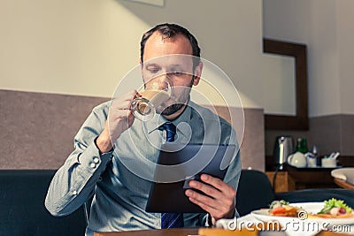 Businessman working on tablet pc during breakfast at home/hotel.