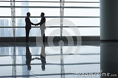 Businessmen Shaking Hands In Airport Terminal