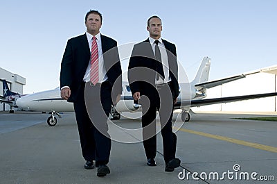 Businessmen walking away from corporate jet