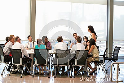 Businesswoman Addressing Meeting Around Boardroom Table