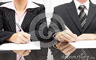 Businesswoman and businessman signing contract after negotiation