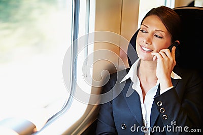 Businesswoman Commuting To Work On Train Using Mobile Phone